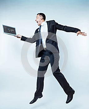 Excited man of business jumping with laptop over background