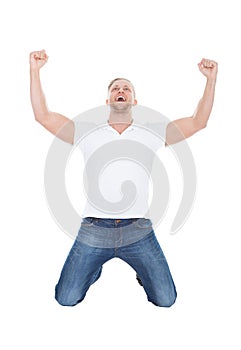 Excited man cheering in jubilation dropping down on his knees