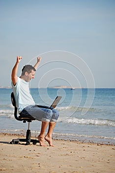 Excited man cheering at laptop