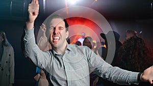 Excited man dancing at nightclub party overjoyed positive emotion discotheque event crowded audience