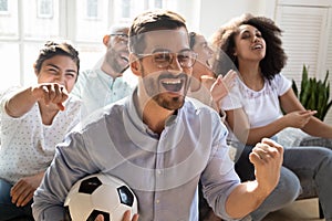 Excited man celebrating goal, watching football with diverse friends