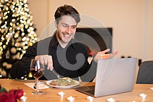 Excited man having dinner during virtual date on laptop