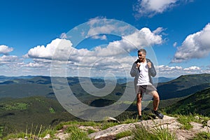 Excited man hiking on a mountain top with backpack enjoy the view and looking for adventures