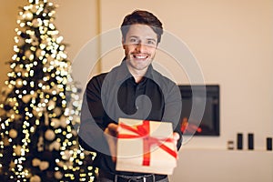 Excited man holding gift box, showing to camera