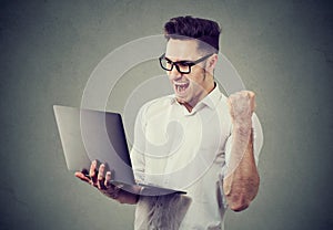 Excited man with laptop computer celebrating success