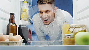 excited man looking into fridge with