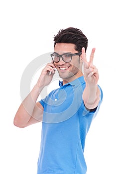 Excited man making victory sign while talking on the phone