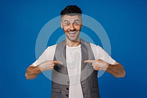 Excited man pointing fingers at himself isolated over blue wall