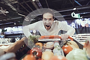 Excited Man with Shopping Trolley in Supermarket.