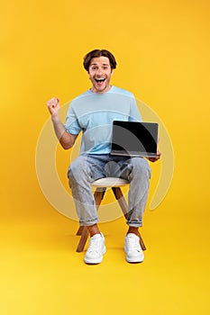 Excited man showing black blank laptop screen screaming yes