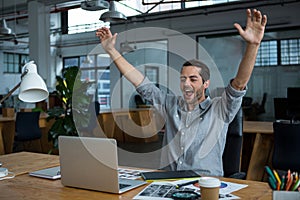 Excited man sitting with laptop at desk