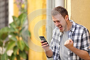 Excited man in the street checking smart phone