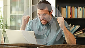 Excited man using a laptop in a coffee shop