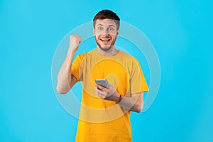 Excited man using mobile phone at studio, celebrating online win