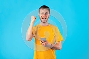 Excited man using mobile phone at studio, celebrating online win