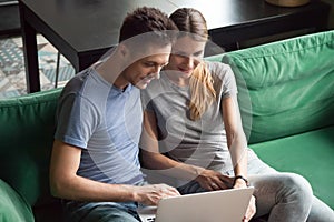 Excited man and woman sitting together and using laptop