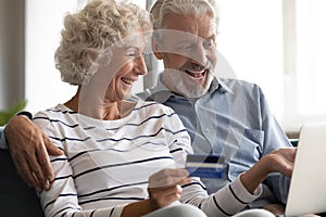 Excited mature couple making payment by credit card online