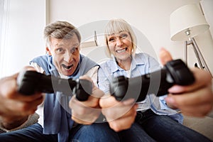 Excited mature couple playing video games at home