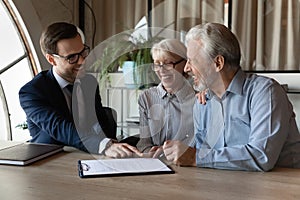 Excited mature couple sign contract with realtor