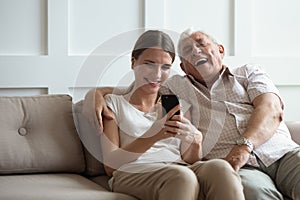 Excited mature dad and adult daughter using smartphone