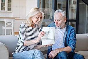 Excited mature man receive box with gift from his loving wife