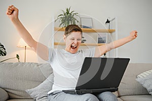 Excited mature woman looking at laptop screen, reading good news in message, celebrating online lottery win, rejoicing