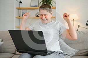 Excited mature woman looking at laptop screen, reading good news in message, celebrating online lottery win, rejoicing