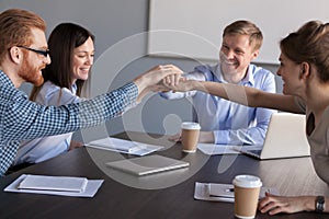 Excited workers join hands engaged in teambuilding activity photo