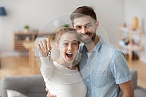 Excited millennial couple holding key to new house photo