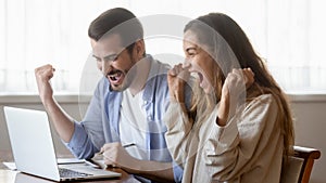 Excited millennial couple triumph reading online news