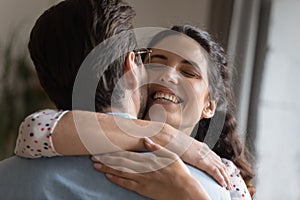 Excited millennial wife embracing beloved husband meeting at home