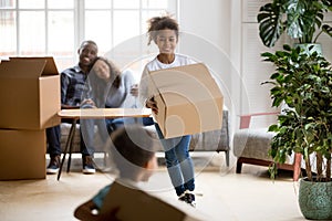 Excited mixed race children holding boxes playing in new home