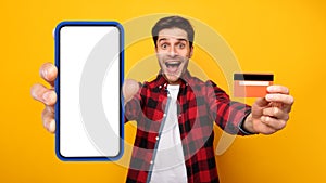 Excited mman showing blank cellphone screen and credit card