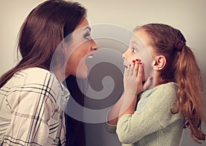 Excited mother and surprising kid girl looking on each other wit
