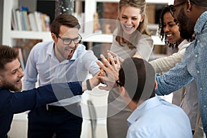Excited motivated multi-ethnic team people give high five in office photo