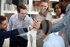 Excited motivated multi-ethnic team people give high five in office