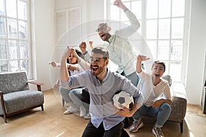 Excited multi-ethnic friends celebrating football victory indoors