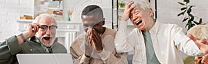 Excited multiethnic pensioners looking at laptop