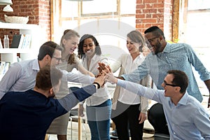 Excited diverse workers join hands at teambuilding activity