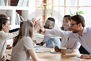 Excited multiracial team giving high five at company meeting photo