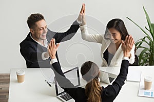 Excited multiracial team holding hands giving high five celebrat