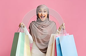 Excited muslim girl holding lot of shopping bags and credit card