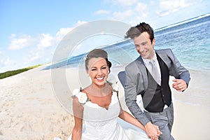 Excited newly-weds running on the beach