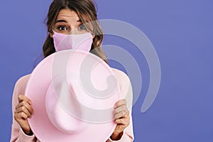 Excited nice girl in protective mask posing with pink hat