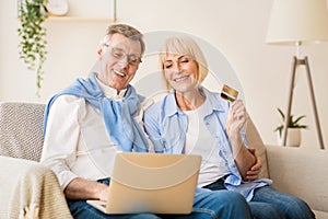 Excited older couple doing online shopping on laptop
