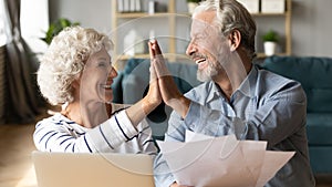 Excited older couple giving high five, celebrating good news