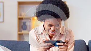 Excited online gamer excited about winning successful mobile game while relaxing at home. Young stylish female enjoying