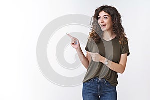 Excited outgoing cheerful caucasian curly-haired girl wearing olive t-shirt smiling amused pointing looking fascinated