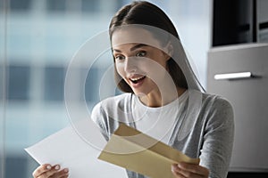 Excited overjoyed millennial woman employee receiving hardcopy of promotion notification