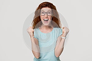 Excited overjoyed young redhead woman feel happy looking at camera